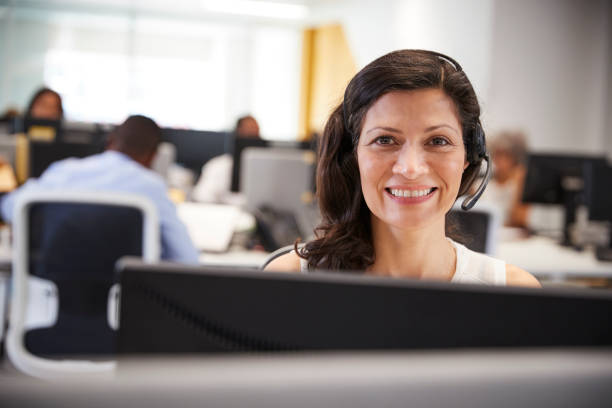 istock Middle aged woman working at computer with headset in office 869286144