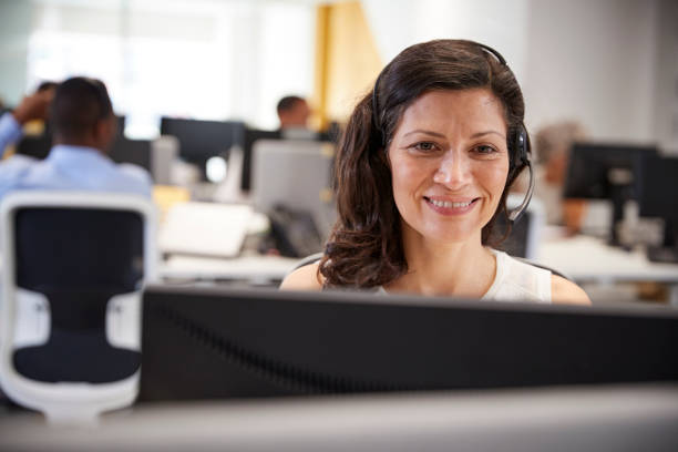 istock Middle aged woman working at computer with headset in office 869286146