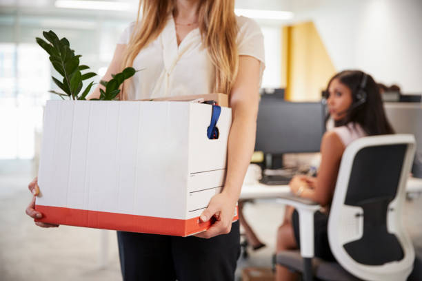 Fired female employee holding box of belongings in an office Fired female employee holding box of belongings in an office being fired photos stock pictures, royalty-free photos & images