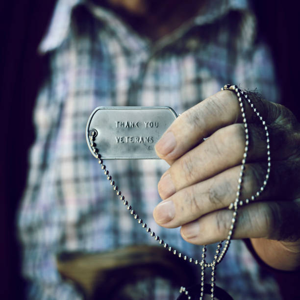 text thank you veterans in a dog tag closeup of an old caucasian man showing a dog tag with the text thank you veterans engraved in it thank you veterans day stock pictures, royalty-free photos & images