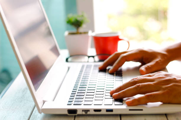 istock Man's hands using laptop with blank screen on desk in home interior. 869291766
