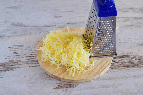 istock Grated cheese on a wooden cutting board with grater. 869294566