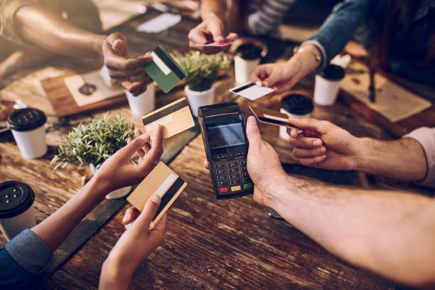 Splitting it six ways High angle shot of a group of friends offering their bank cards to pay the bill at a cafe restaurant table card stock pictures, royalty-free photos & images