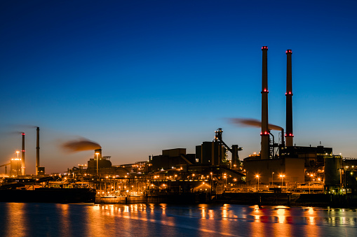 A large steelworks on the river illuminated at night in industrial district near Amsterdam, Netherlands.