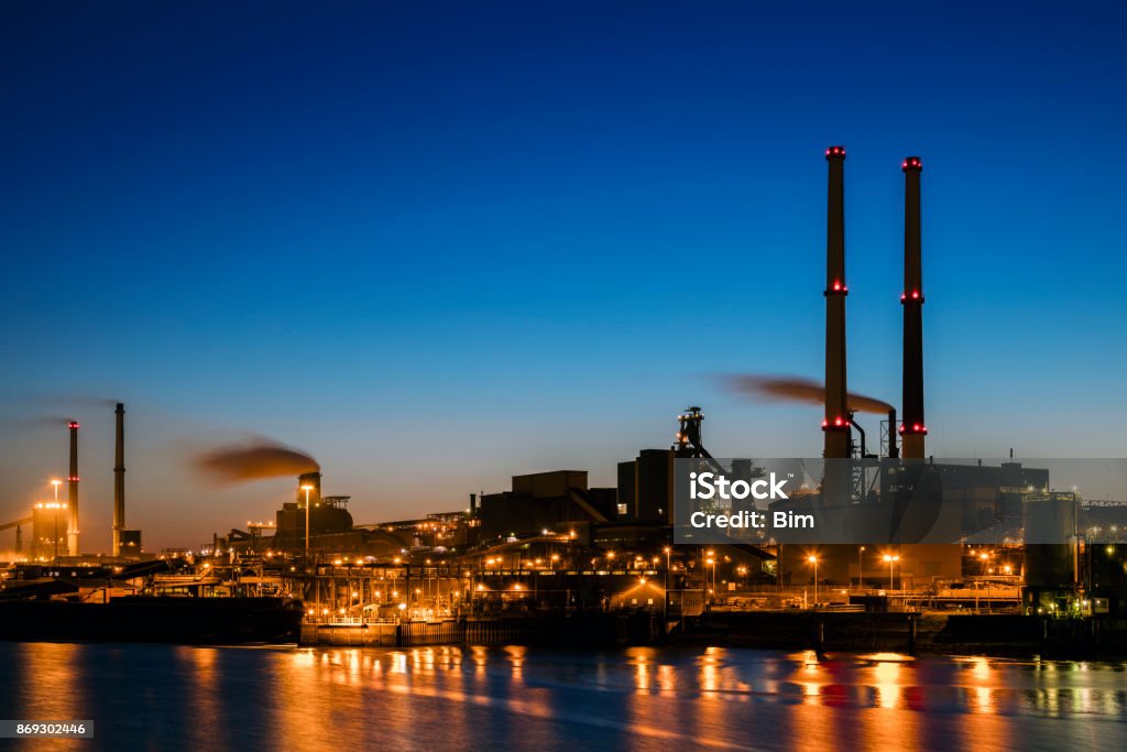 Industrial plant at twilight A large steelworks on the river illuminated at night in industrial district near Amsterdam, Netherlands. Night Stock Photo