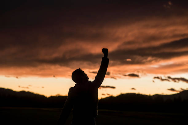 istock Jubilant man raising his fist against a sunset 869306502