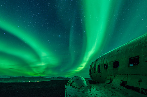 Intense green aurora borealis dancing over the DC plane wreck in Sólheimasandur Iceland