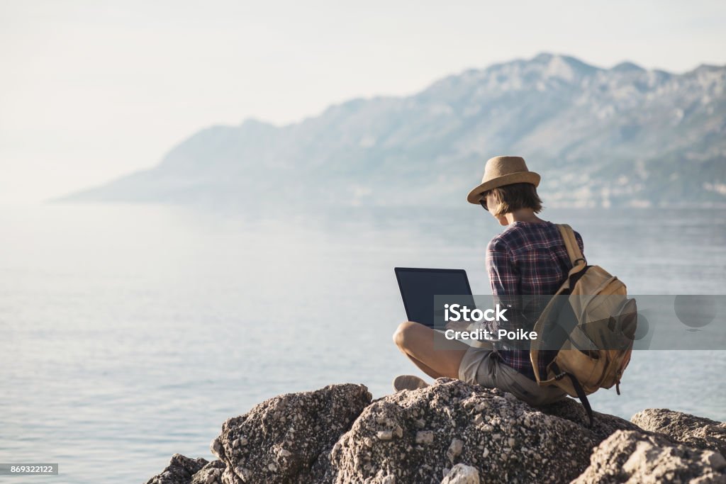 Joven mujer utilizando la computadora portátil cerca del mar - Foto de stock de Trabajo freelance libre de derechos
