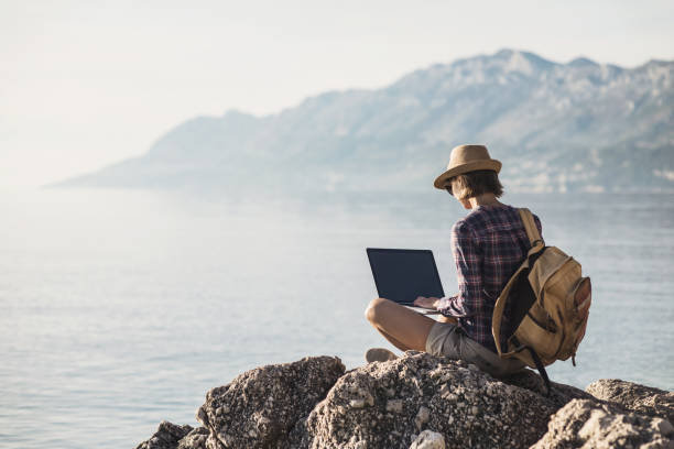 istock Young woman using laptop near the sea 869322122