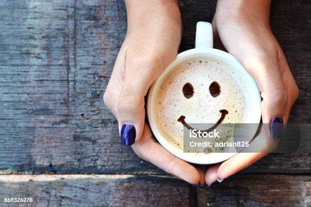 Smiley Face On Cappuccino Foam Woman Hands Holding One Cappuccino Cup On Wooden Table Stock Photo - Download Image Now