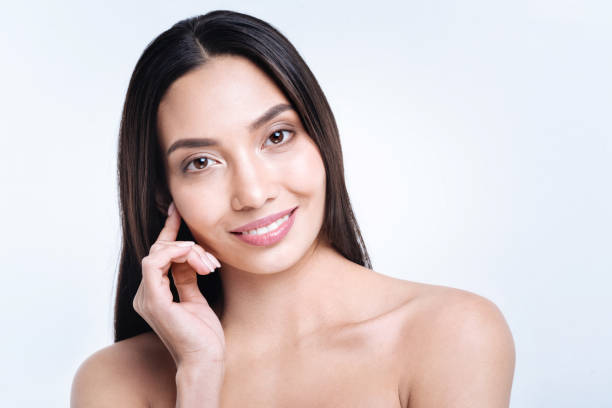 istock Cheerful dark-haired woman touching earlobe while posing 869329328