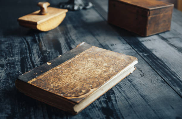 istock Old antique book and other objects on black wooden table 869334756