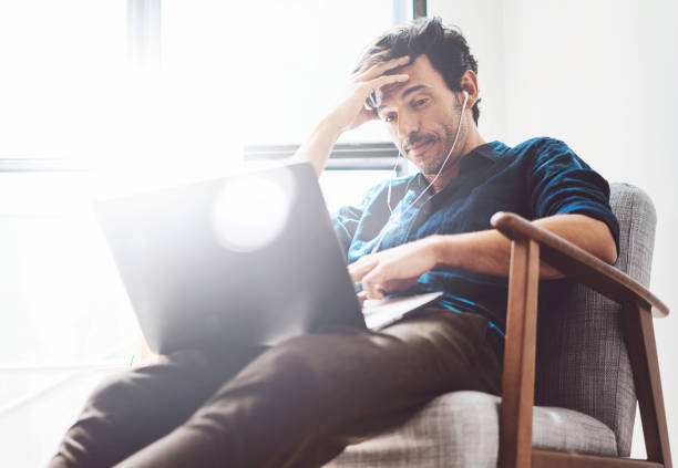 istock Young man working at home.Man using contemporary laptop and headphones while sitting in vintage chair.Blurred background. Horizontal.Side view. 869345880