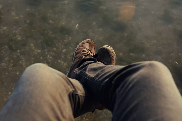 Man dangling feet over water