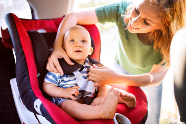 junge mutter putting babyjungen in den kindersitz. - equipment conformity car transportation stock-fotos und bilder