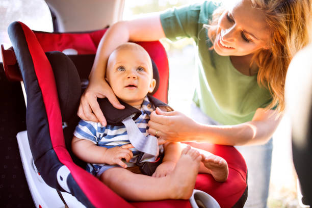 年輕的母親把男嬰放在汽車座椅上。 - 嬰兒安全座椅 圖片 個照片及圖片檔