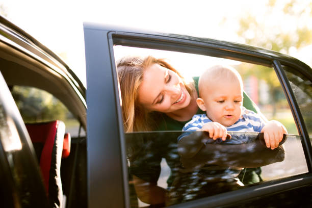 junge mutter mit ihrem kleinen baby-jungen durch das auto stehen. - furniture barefoot little boys family stock-fotos und bilder