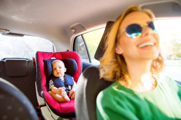 joven madre con su pequeño bebé en el coche. - rear view mirror car mirror sun fotografías e imágenes de stock