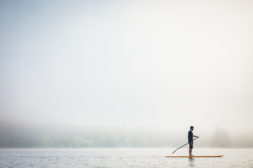 A young man practicing SUP - Stand-up Paddleboard