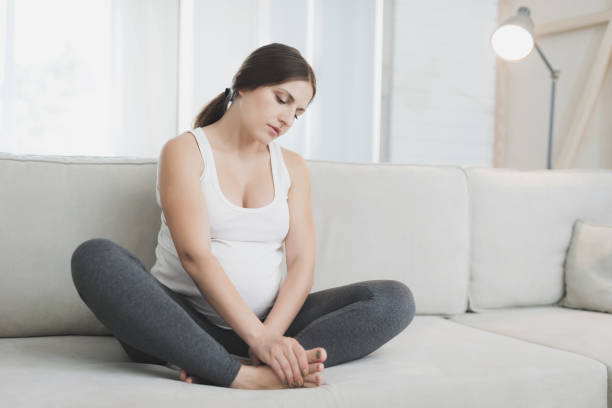 istock A pregnant woman sits at home on a light sofa. Her legs hurt 869363014