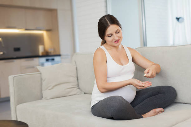 istock A pregnant woman sits at home on a light sofa. She's getting ready to take a pill 869363742