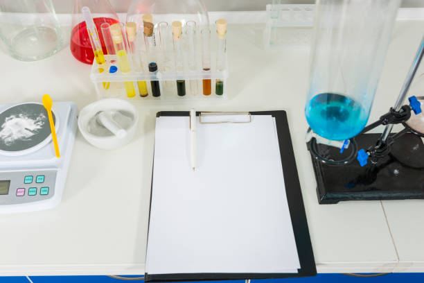 Clipboard with report near test tubes and flasks with different liquid. Healthcare and biotechnology concept