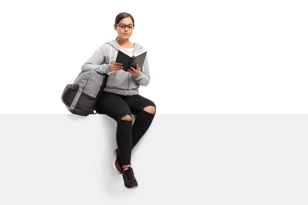 istock Female teenage student seated on a panel reading a book 869371610