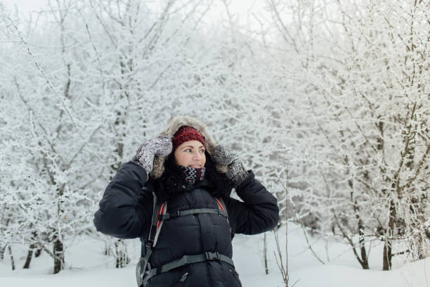 istock Smiling woman dressed warm walking through forest in winter. 869375900