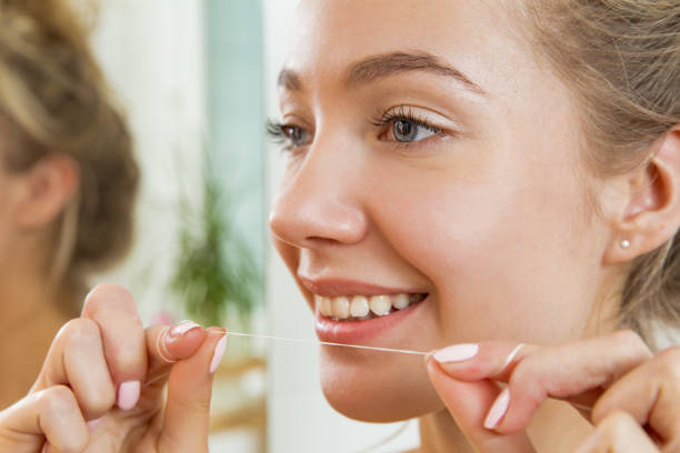 istock Young beautiful woman flossing her teeth 869378306