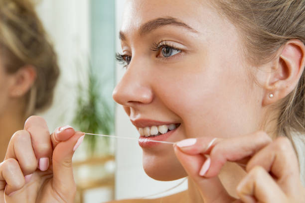 istock Young beautiful woman flossing her teeth 869378470