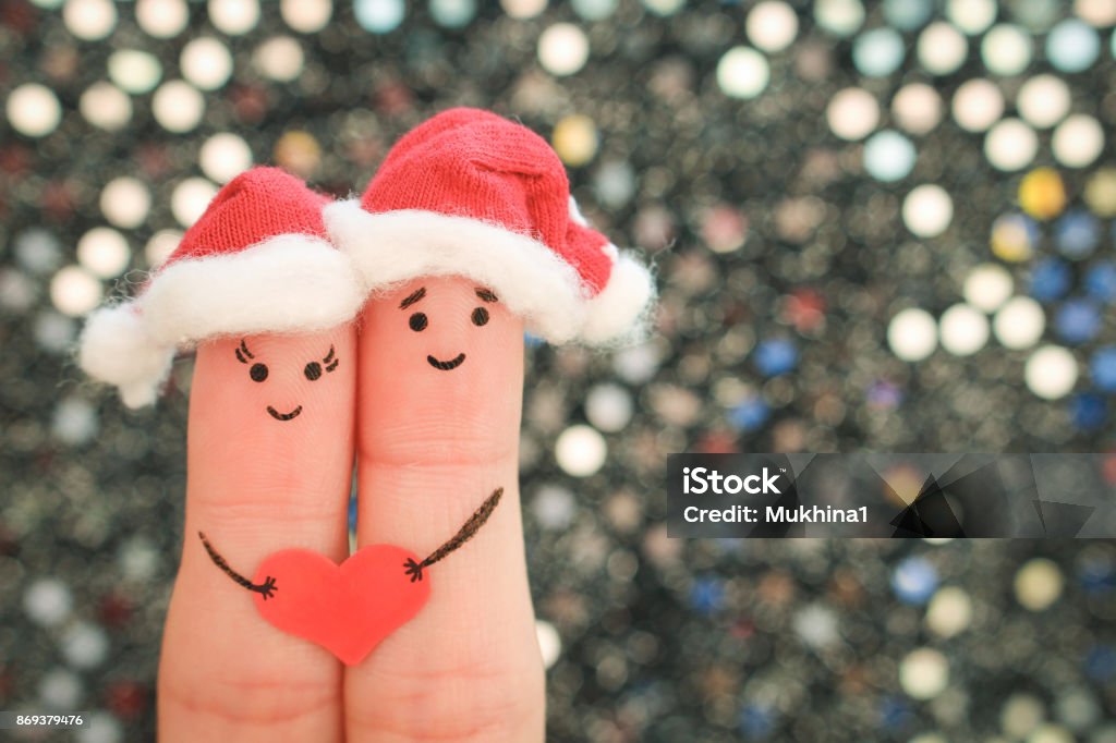 Fingers art of couple celebrates Christmas in new year hats. Toned image. Christmas Stock Photo