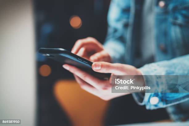 Closeup View Of Female Hands Holding Modern Smart Phone And Pointing Fingers On The Touch Screen At Nighthorizontal Blurred Background Bokeh Effects Stock Photo - Download Image Now