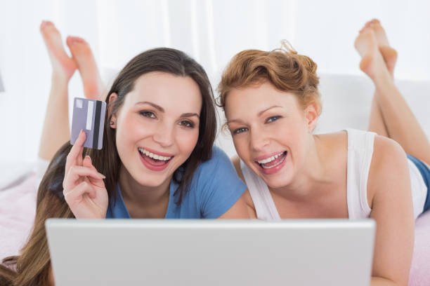 istock Cheerful relaxed friends doing online shopping in bed 869386636