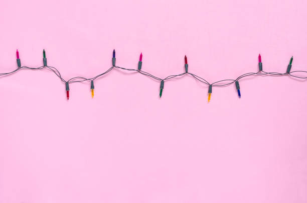 Christmas light bulbs on string in multi colours; blue, yellow, red, pink & green on pink background with copy space for Xmas text decoration, new year or special event celebration (tree ornament concept) bombillas de luz de navidad en cuerda en múltiples colores; azul, amarillo, rojo, rosa y verde sobre fondo rosa con espacio de copia de texto decoración de navidad, año nuevo o celebración de eventos especiales (concepto de adorno de árbol)