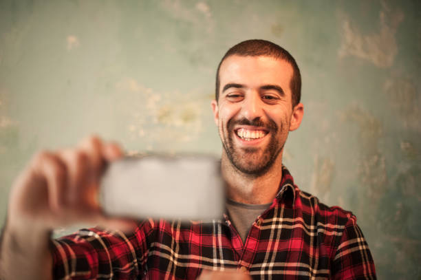 istock Young Attractive Man with Beard Taking Selfie Indoors 869398744