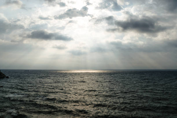 istock Dramatic Light Rays Coming From The Overcast Sky Over Stormy Sea 869402102