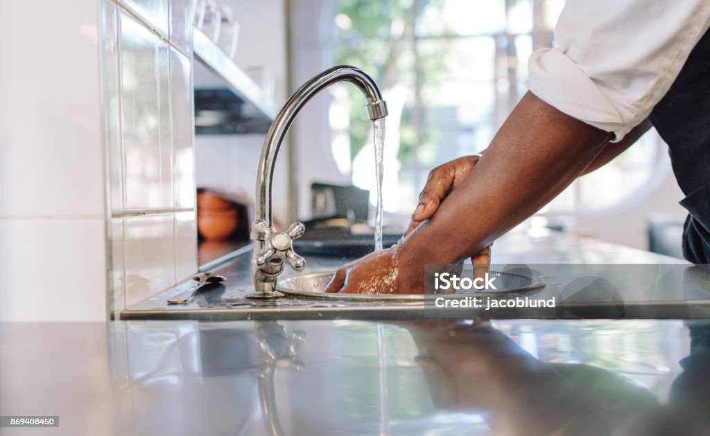 Chef washing his hands in commercial kitchen Close up of chef washing his hands in commercial kitchen. Man washing hands in a sink with tap water. Washing Hands Stock Photo