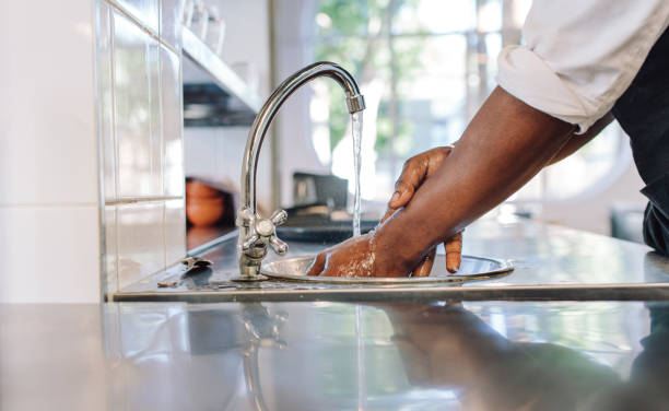 Chef washing his hands in commercial kitchen Close up of chef washing his hands in commercial kitchen. Man washing hands in a sink with tap water. food hygene stock pictures, royalty-free photos & images