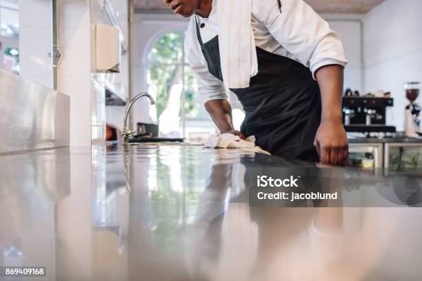 Waiter Wiping The Counter Top In The Kitchen Stock Photo - Download Image Now - Cleaning, Commercial Kitchen, Kitchen