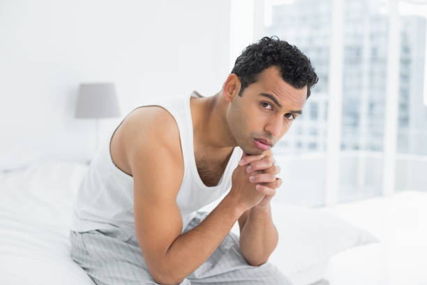 istock Portrait of a serious man sitting on bed 869415964