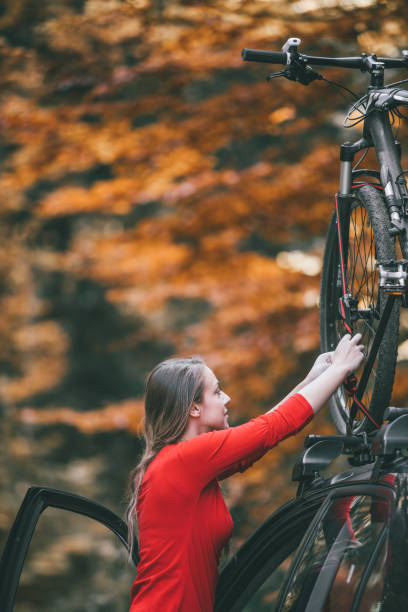 istock Woman adjusting bikes car on roof rack 869416620