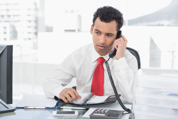 istock Businessman with diary using land line phone at office 869424070
