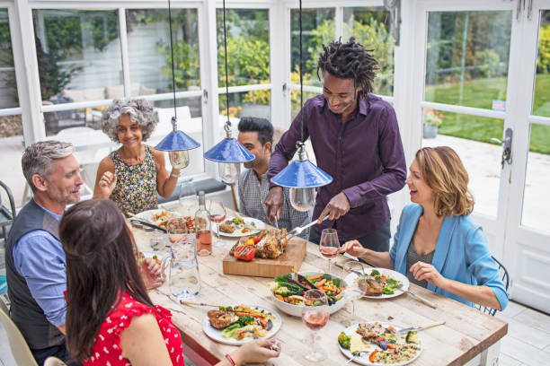 istock Man carving meat to serve friends at dining table 869426516