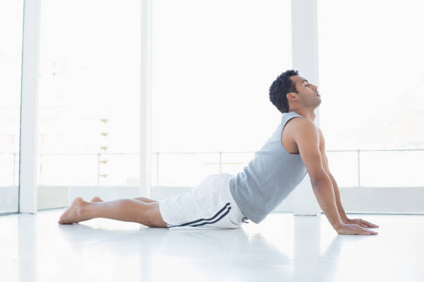 istock Fit young man doing the cobra pose in fitness studio 869440008