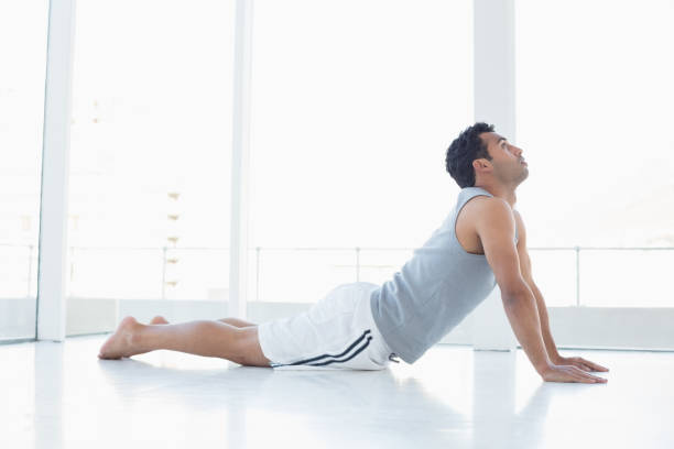 istock Fit young man doing the cobra pose in fitness studio 869440016