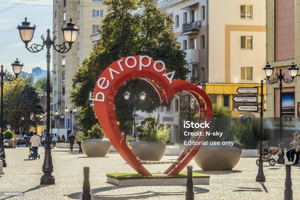 Street of the fiftieth anniversary of the Belgorod region. Pedestrian street in the old residential center of the city. Bench of love in the shape of a heart with flower pots. Belgorod, Russia. Belgorod, Russia - September 29, 2017: Street of the fiftieth anniversary of the Belgorod region. Pedestrian street in the old residential center of the city. Urban environment. Bench of love in the shape of a heart with flower pots. Architecture Stock Photo