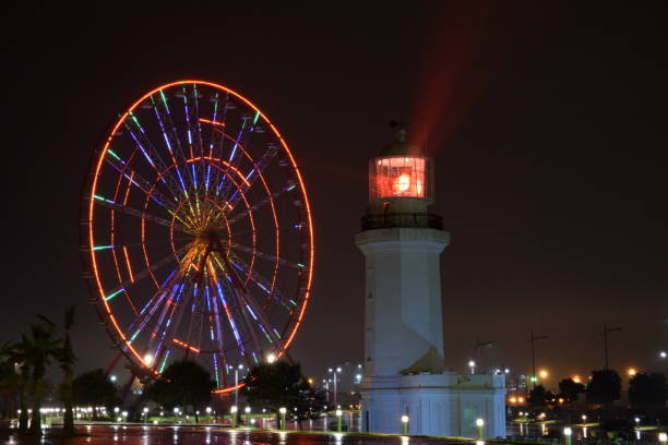 istock Batumi lighthouse and Ferris Wheel colored in red during a rainy night 869448134