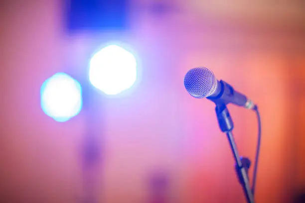 microphone with bokeh light in concert hall or conference room soft and blur style for background.Microphone over the Abstract blurred photo of conference hall or seminar room back