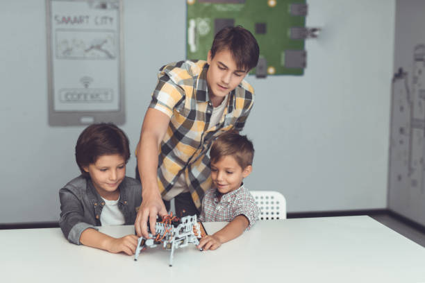 istock The young guy brought two boys a gray robot. Children are enthusiastic about robot 869452446