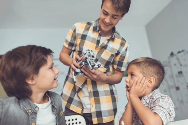 istock The young guy brought two boys a gray robot. Children are enthusiastic about robot 869452688